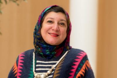 Dr Eiman Abdel Meguid, Women wearing multicoloured head covering, tucked neatly into a colourful geometric patterned jumped and waering a twisted metal and beading necklace.